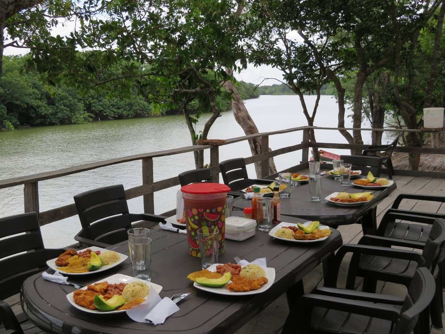 Mesa servida con platos de comida en el deck, con el río detrás.