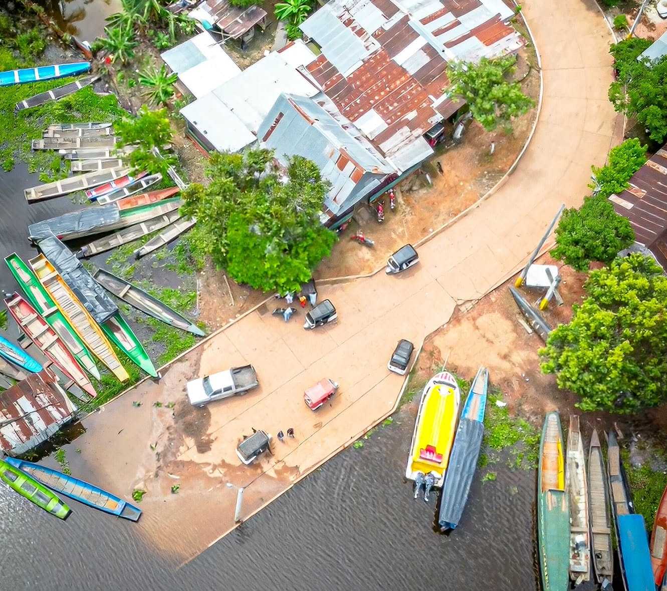 El borde del pueblo desde el dron, más de cerca: los techos, la calle que baja al puerto y las canoas en fila.
