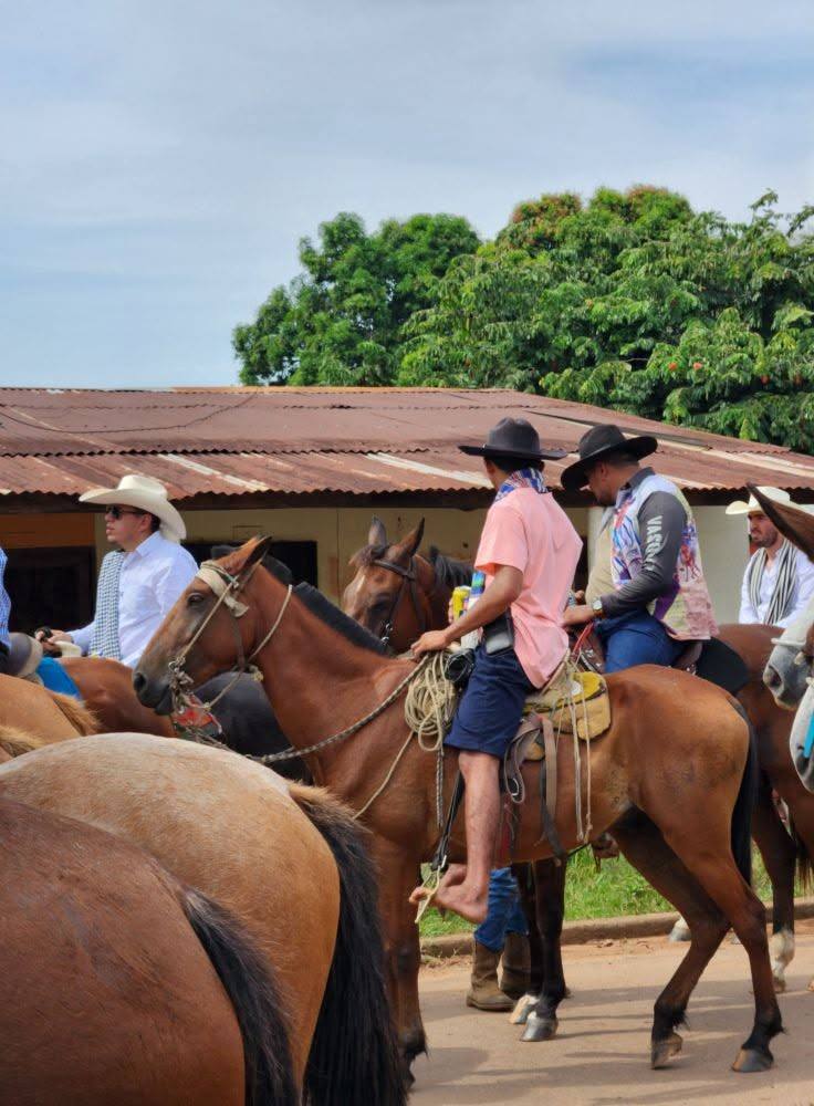 Jinetes de sombrero a caballo en una calle del pueblo.