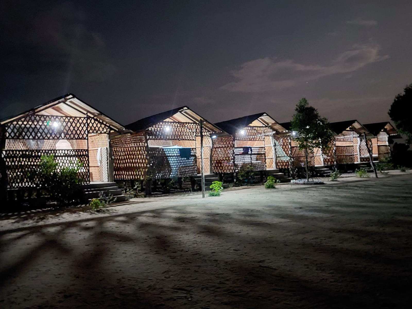 Fila de cabañas iluminadas por dentro durante la noche.