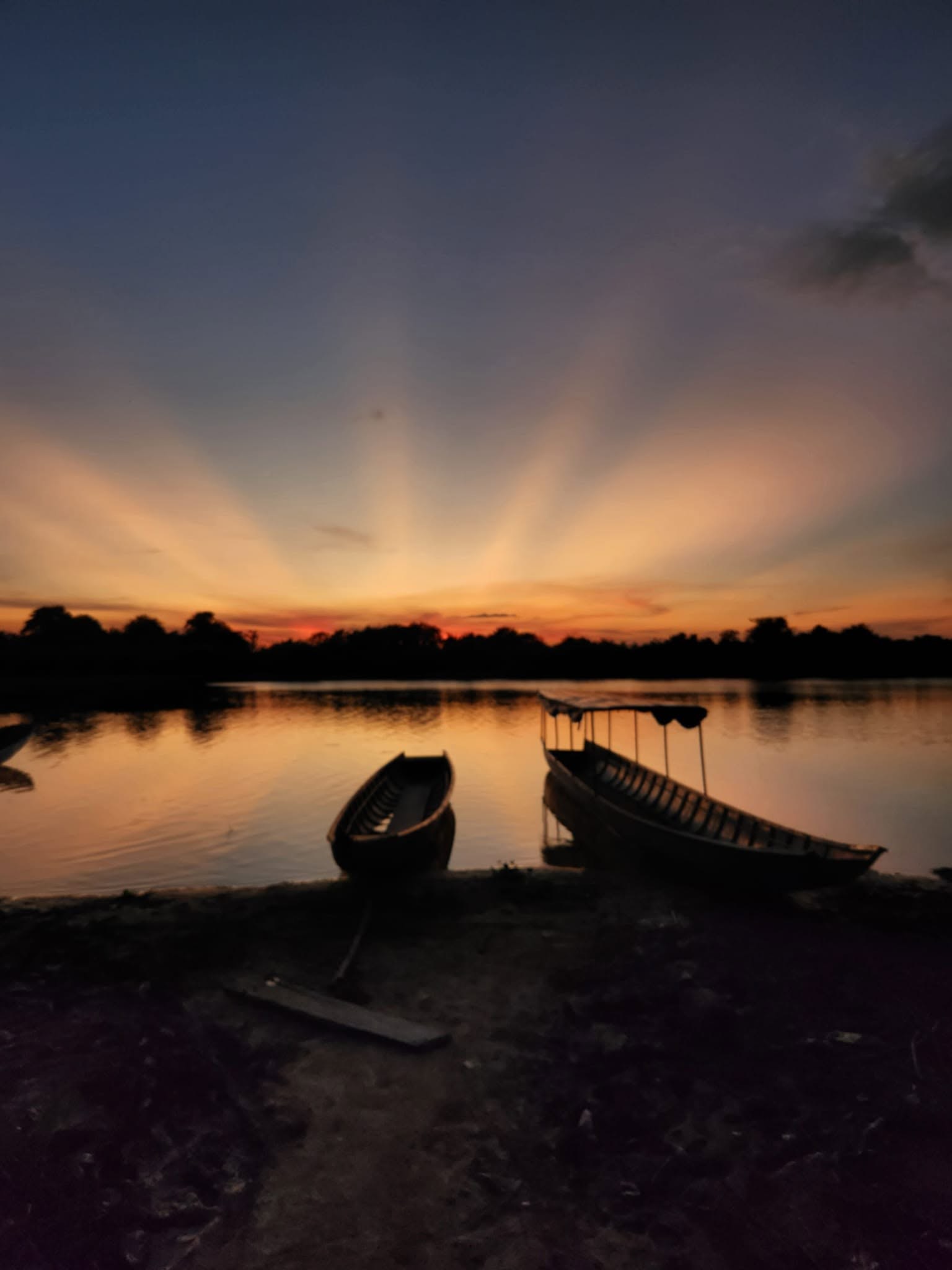 Canoas en la orilla de la laguna con rayos de sol al atardecer.