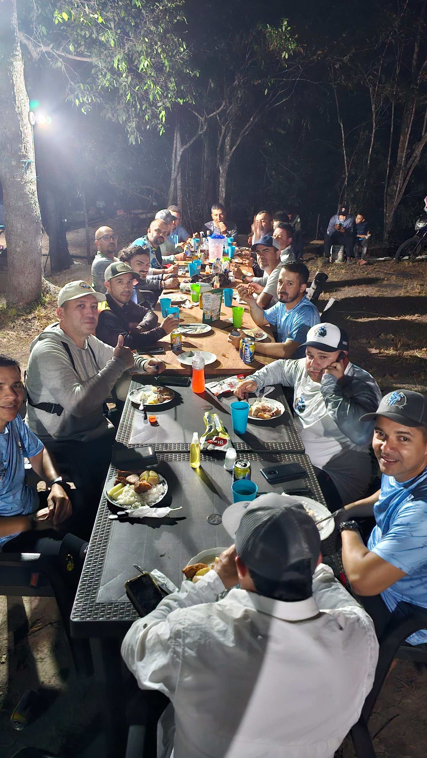Mesa larga de noche con pescadores cenando juntos.