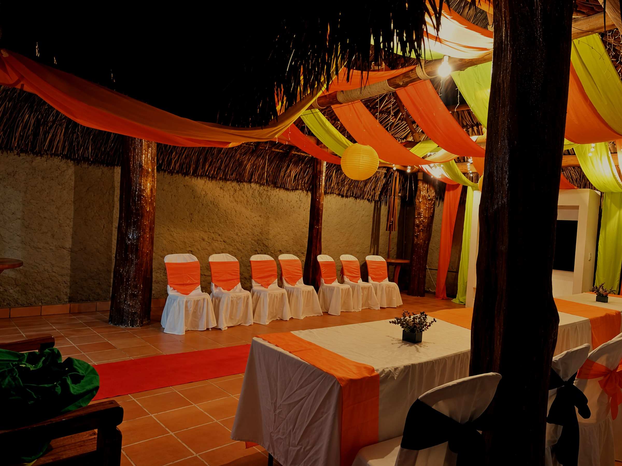 Kiosko de noche con telas de colores y sillas vestidas alrededor de las mesas.