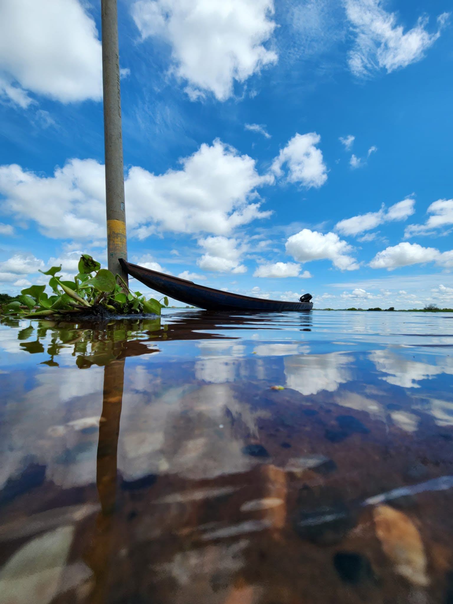Invierno: una canoa en la laguna llena, con las nubes reflejadas en el agua.