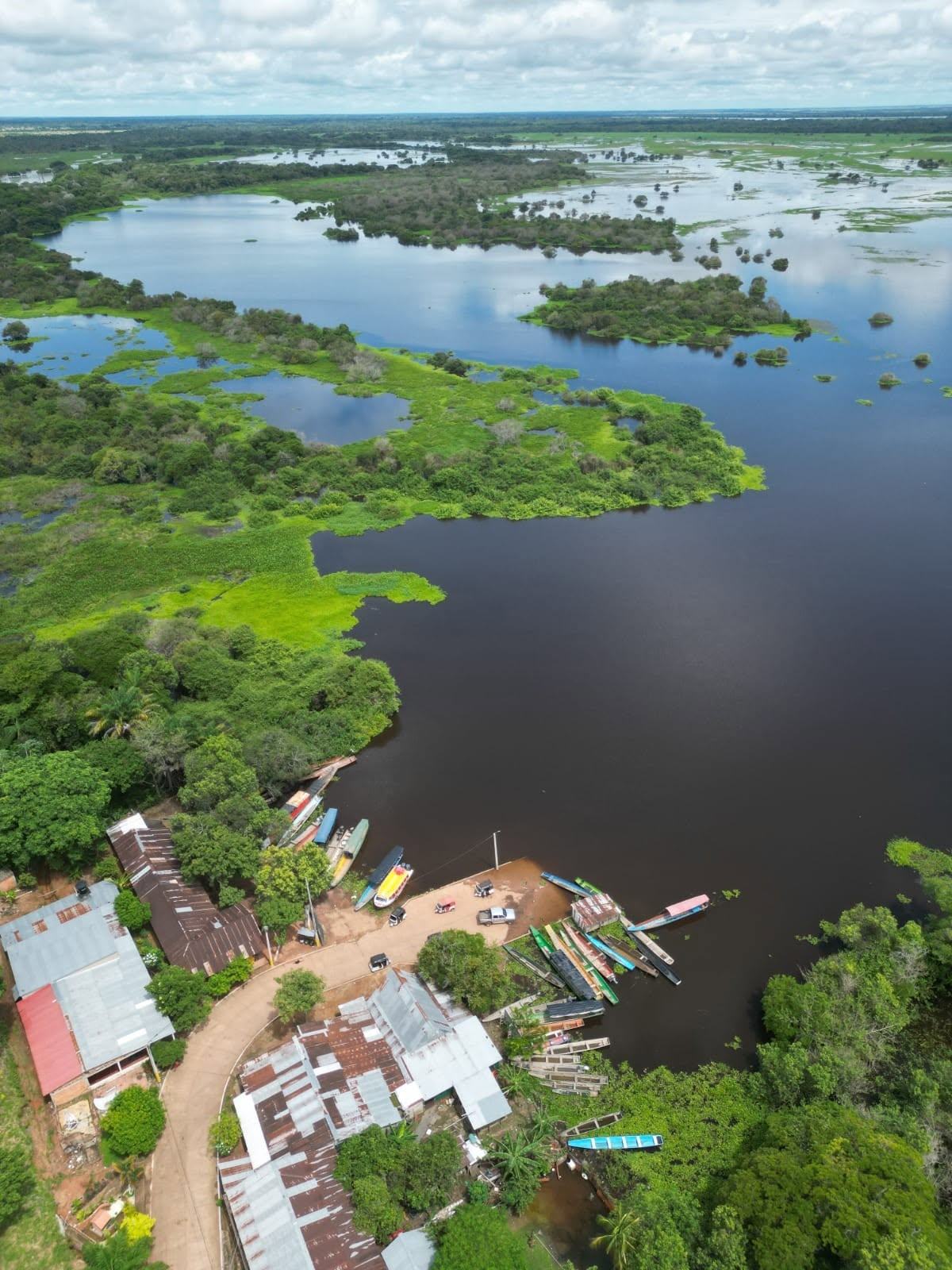 El puerto del pueblo en la laguna, con canoas y un yate, visto desde lo alto.