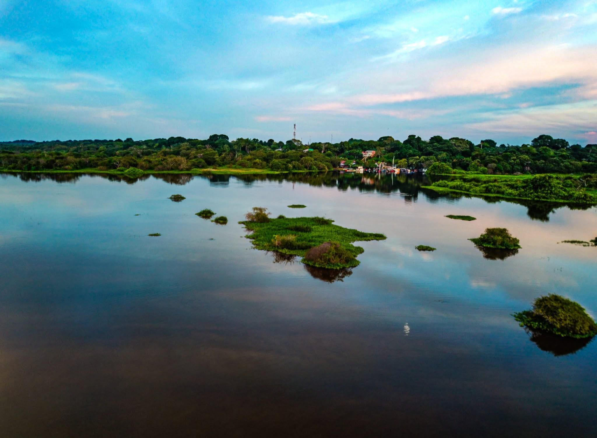 La laguna de La Primavera con islas de vegetación, bajo un cielo azul.