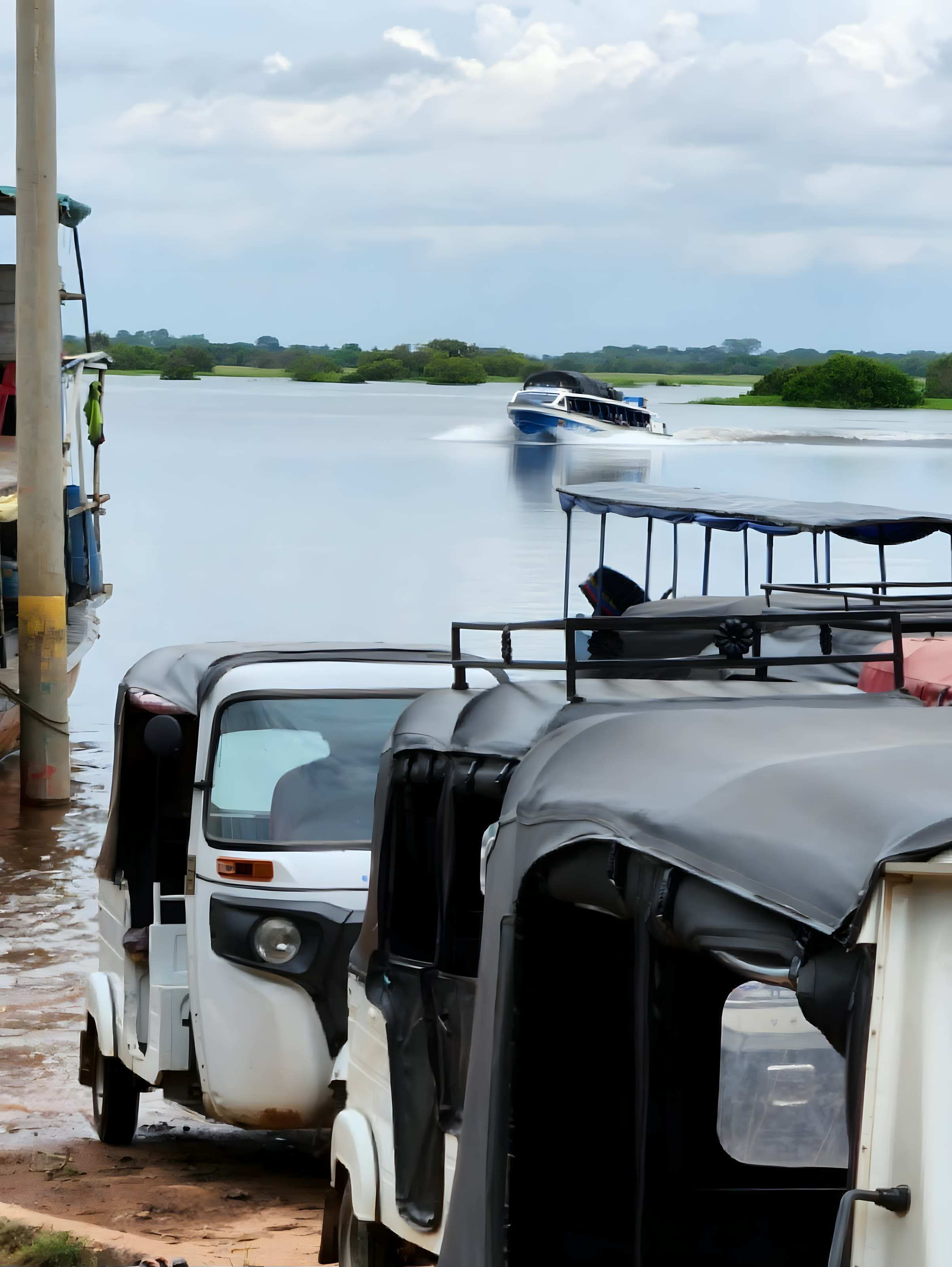 Mototaxis estacionados en el puerto de La Primavera mientras un yate llega por el agua.