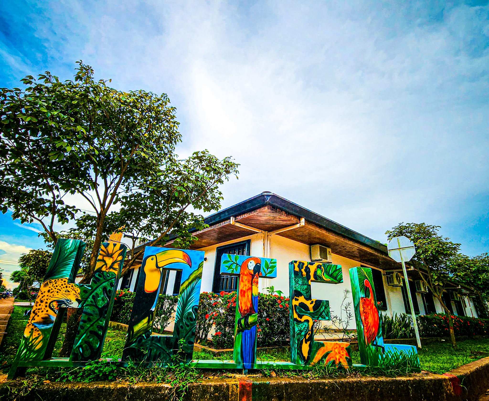 Muro exterior pintado con un mural de colores frente al hotel, bajo un cielo azul.