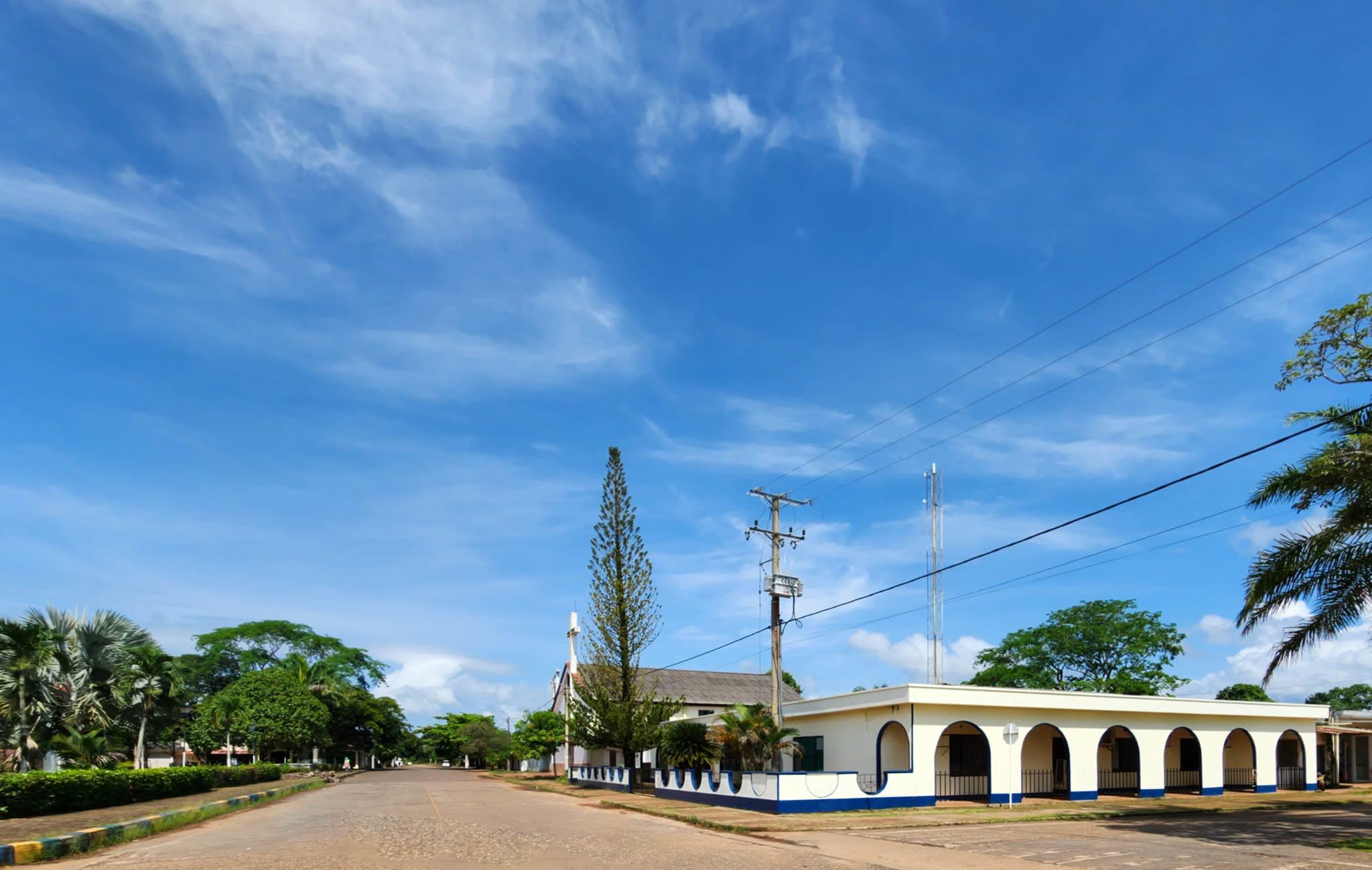 El palacio municipal de La Primavera, blanco con arcos azules, junto a una avenida.