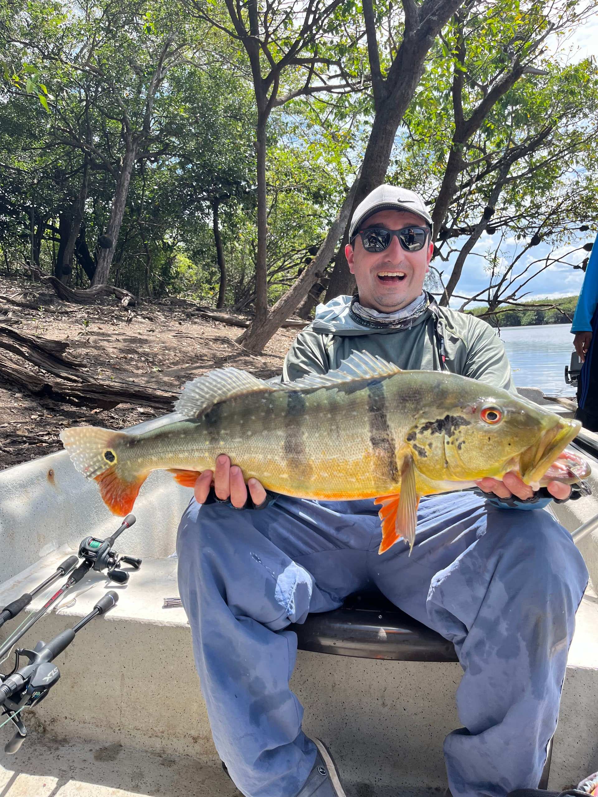 Pescador sentado en la lancha con un pavón sobre las piernas.