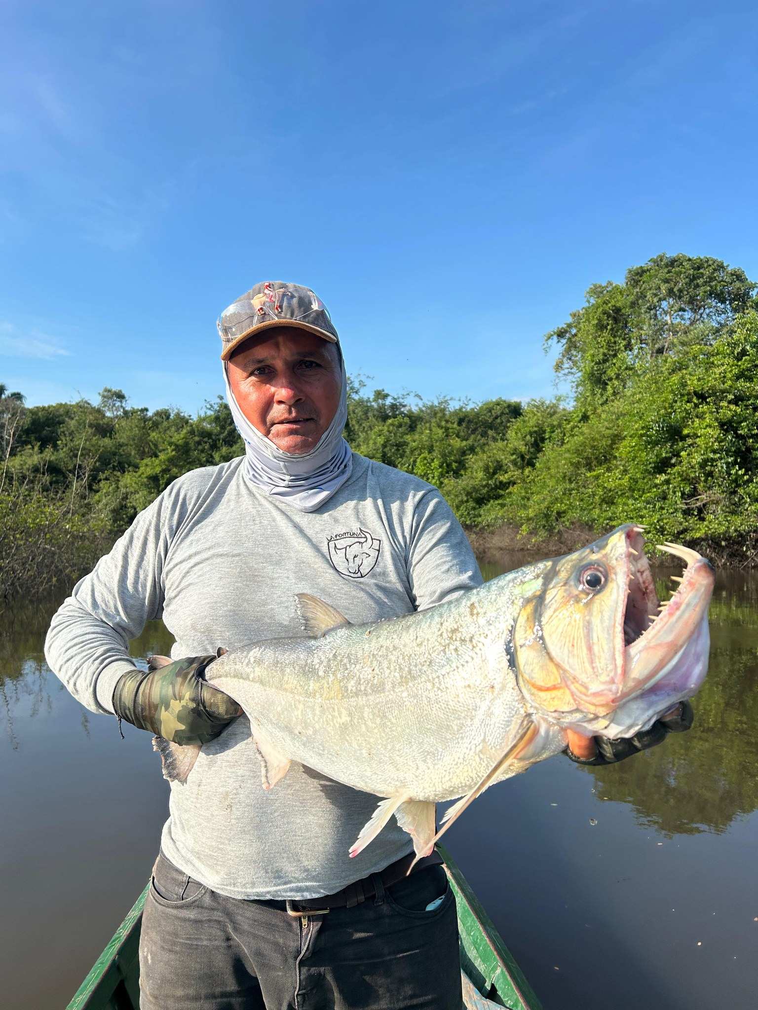 Pescador en una curiara muestra una payara con la boca abierta y los colmillos largos a la vista.