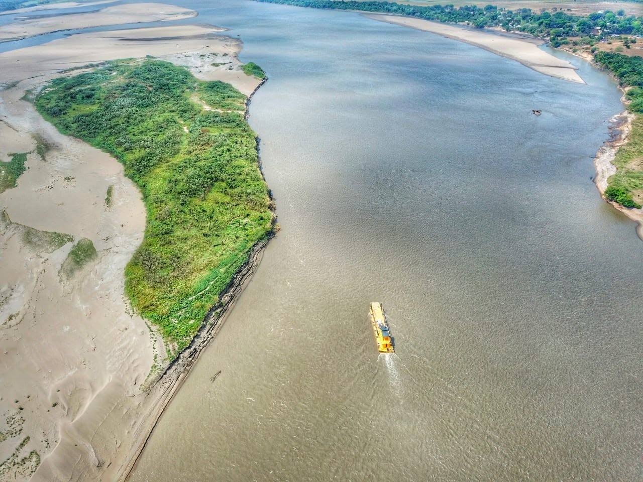 El río Meta con una isla verde y un bote amarillo, desde lo alto.
