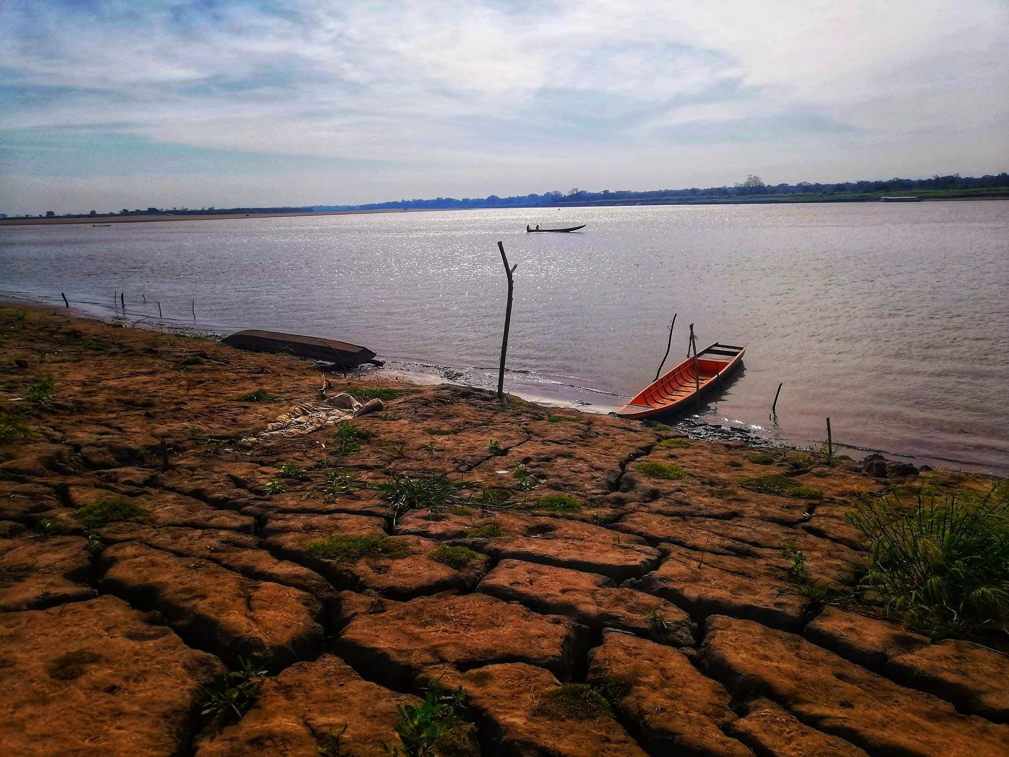 La orilla del río Meta agrietada en verano, con una canoa roja junto al agua.