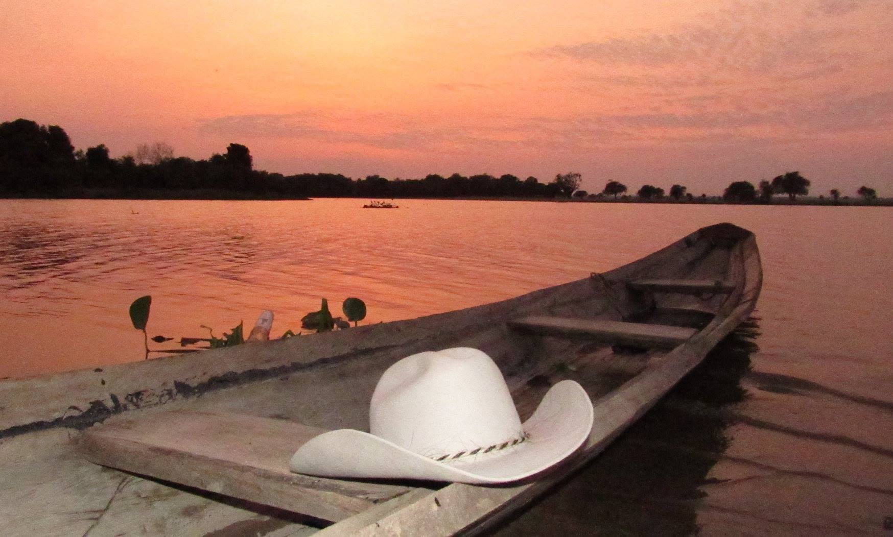 Sombrero blanco en una canoa al atardecer.